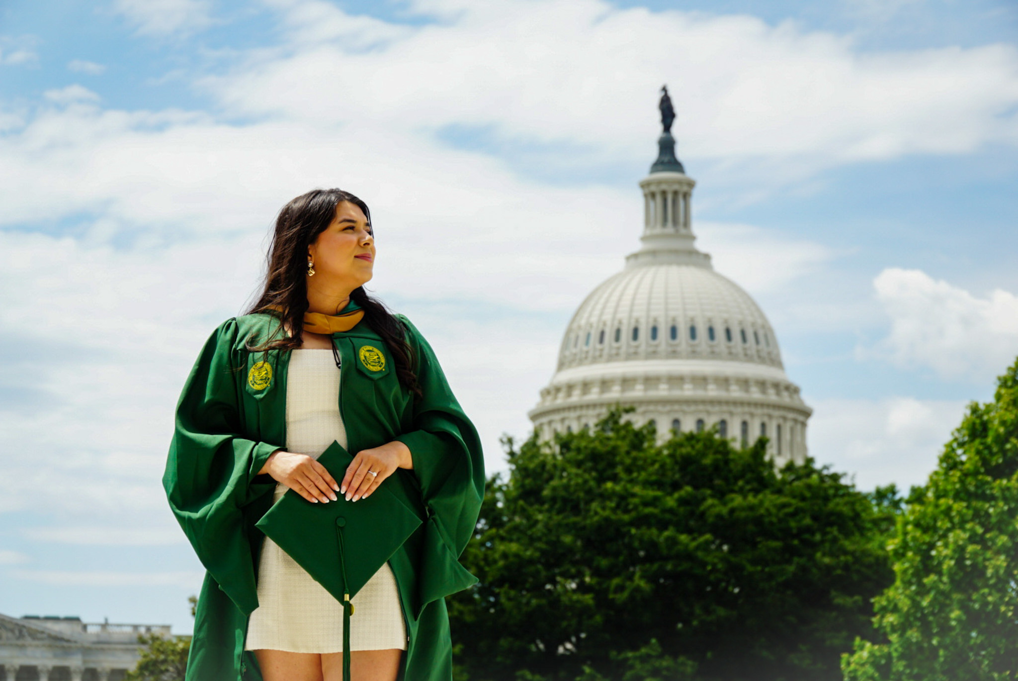 Graduate in cap and gown in front of the U.S. Capitol dome