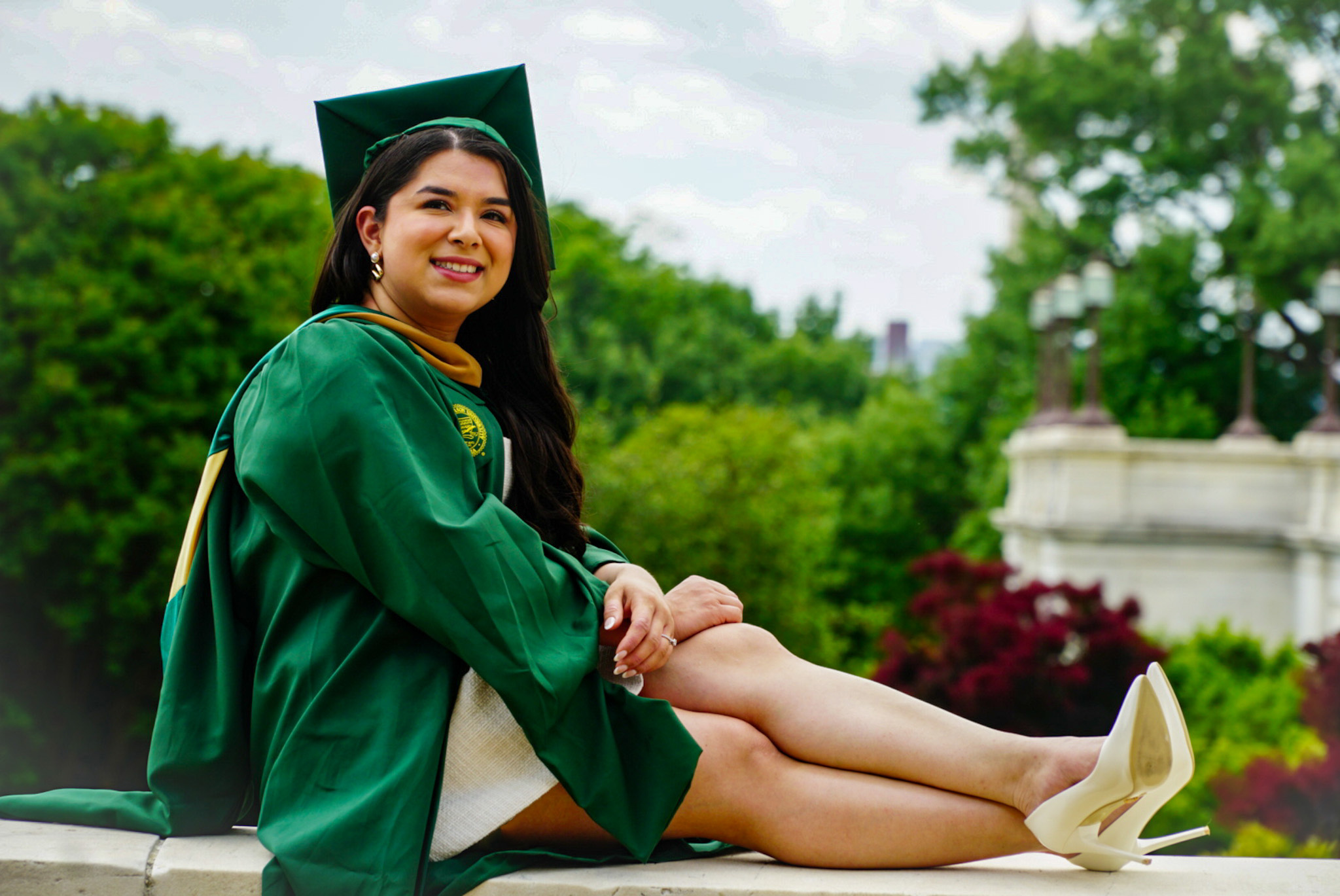 Graduate seated and smiling in cap and gown
